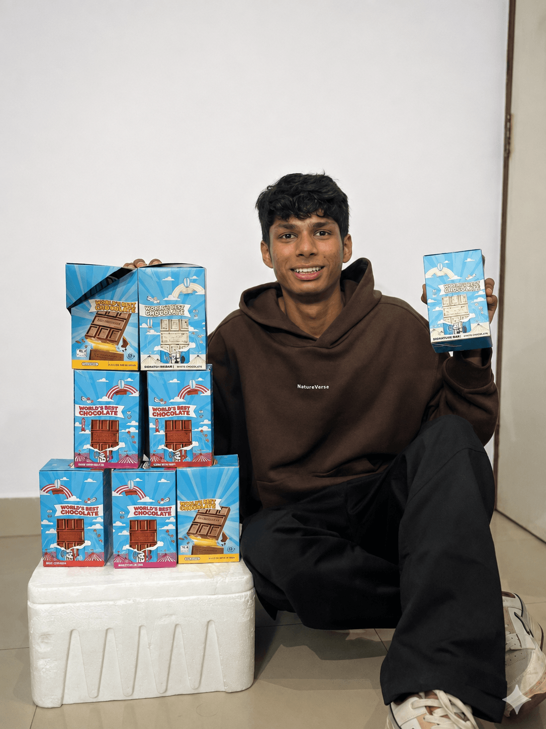Kana Mundra seated beside a stack of Feastables boxes