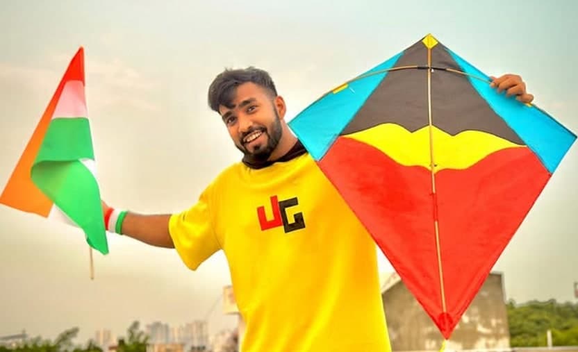 TechnoGamerz holding the Indian flag and a kite on a rooftop
